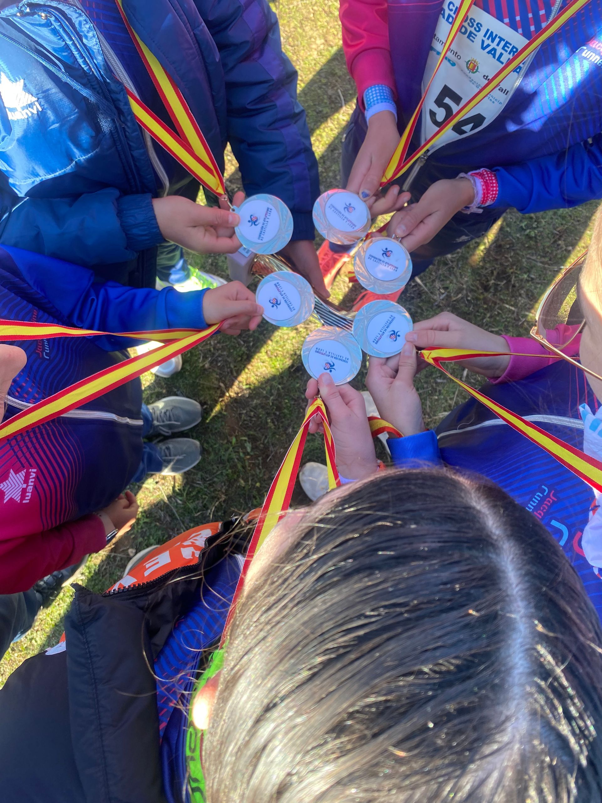 Grupo de personas sosteniendo medallas, al aire libre, día soleado.